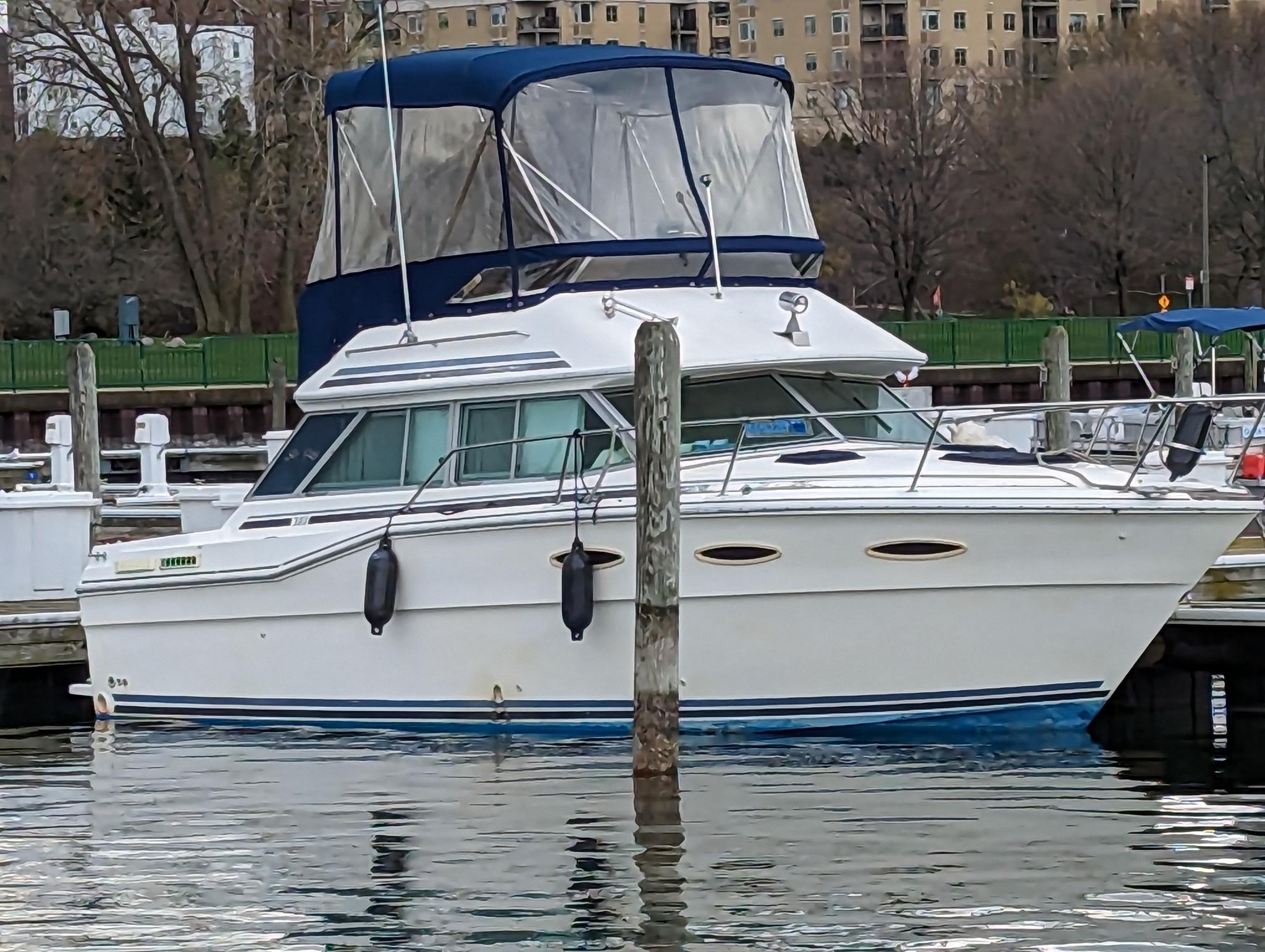 Sea Ray 300 SD 1986 Sea Ray 300 SD boat docked at a marina with blue canopy.