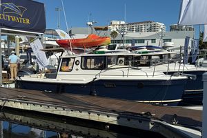 Ranger Tugs R-25 2026 Ranger Tugs R-25 boat docked at marina, featuring sleek design and vibrant kayak on top.