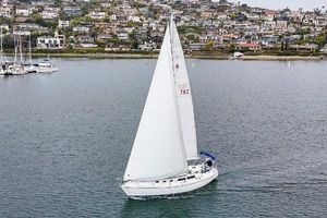 Catalina 34 1989 Catalina 34 sailboat cruising on calm waters near a coastal town.