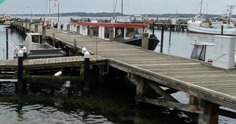 Custom Stahlschute Prahm Hausboot Docked 1950 Stahlschute Prahm Hausboot at a wooden pier, surrounded by calm waters.