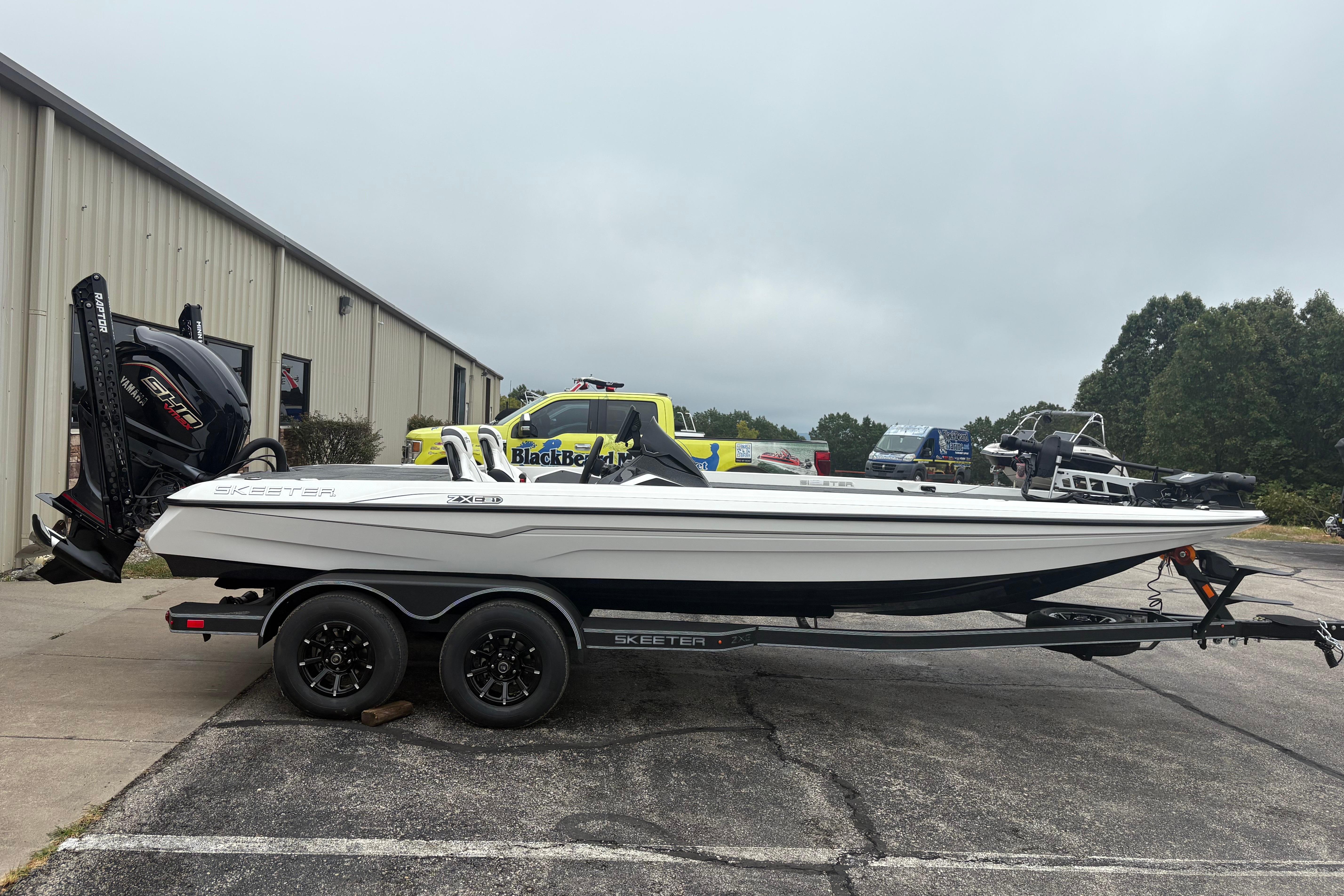 Skeeter ZXE21 2026 Skeeter ZXE21 boat on trailer, parked outdoors near industrial building.