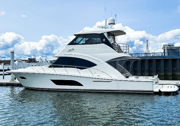 Riviera 57 Enclosed Flybridge 2023 Riviera 57 Enclosed Flybridge yacht docked at marina under blue sky.