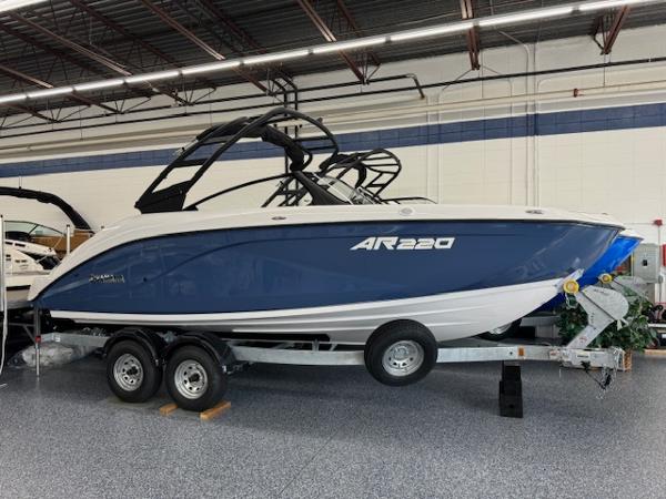 Yamaha Boats AR220 2025 Yamaha AR220 boat on trailer in showroom, blue and white design.