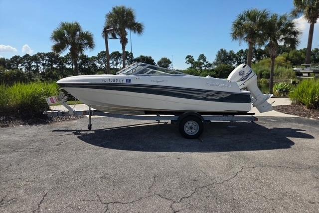 Four Winns 180 Horizon 2001 Four Winns 180 Horizon boat on trailer, parked outdoors with palm trees in background.