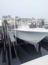 Sailfish 270 CC 2015 Sailfish 270 CC boat docked at marina, surrounded by calm water and palm trees.