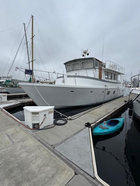 Custom PILOTHOUSE MOTORYACHT 1986 Custom PILOTHOUSE MOTORYACHT docked, with a small blue kayak nearby.