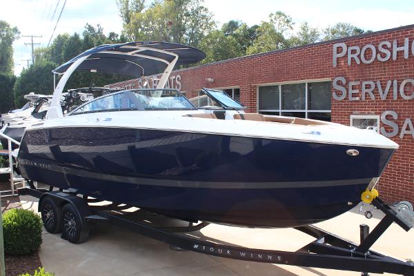 Four Winns H6 2025 Four Winns H6 boat on trailer, parked outside a service building.