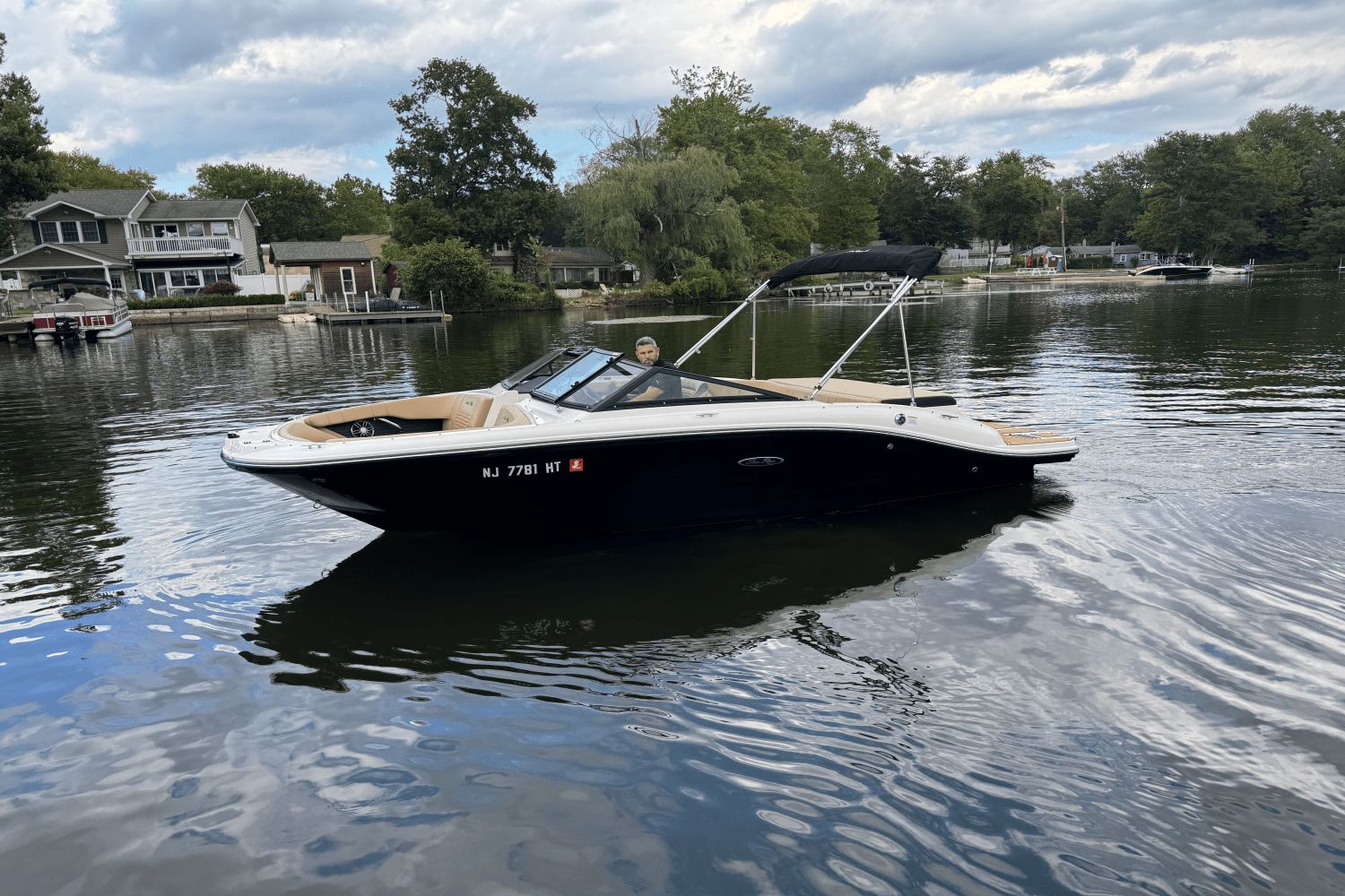 Sea Ray 190 Sport 2023 Sea Ray 190 Sport boat on a calm lake with houses in the background.