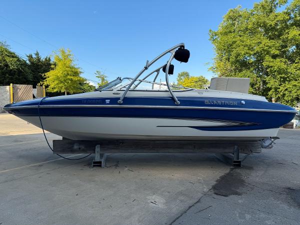 Glastron GX 235 2006 Glastron GX 235 boat on trailer, blue and white, parked outdoors.