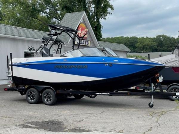 Moomba Craz 2024 Moomba Craz boat in blue and white on a trailer at a dealership.