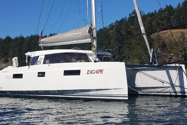 Nautitech 40 Open 2016 Nautitech 40 Open catamaran named "Escape" on calm water near forested shoreline.