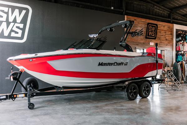MasterCraft XT22 2025 MasterCraft XT22 boat in showroom, red and white design on trailer.