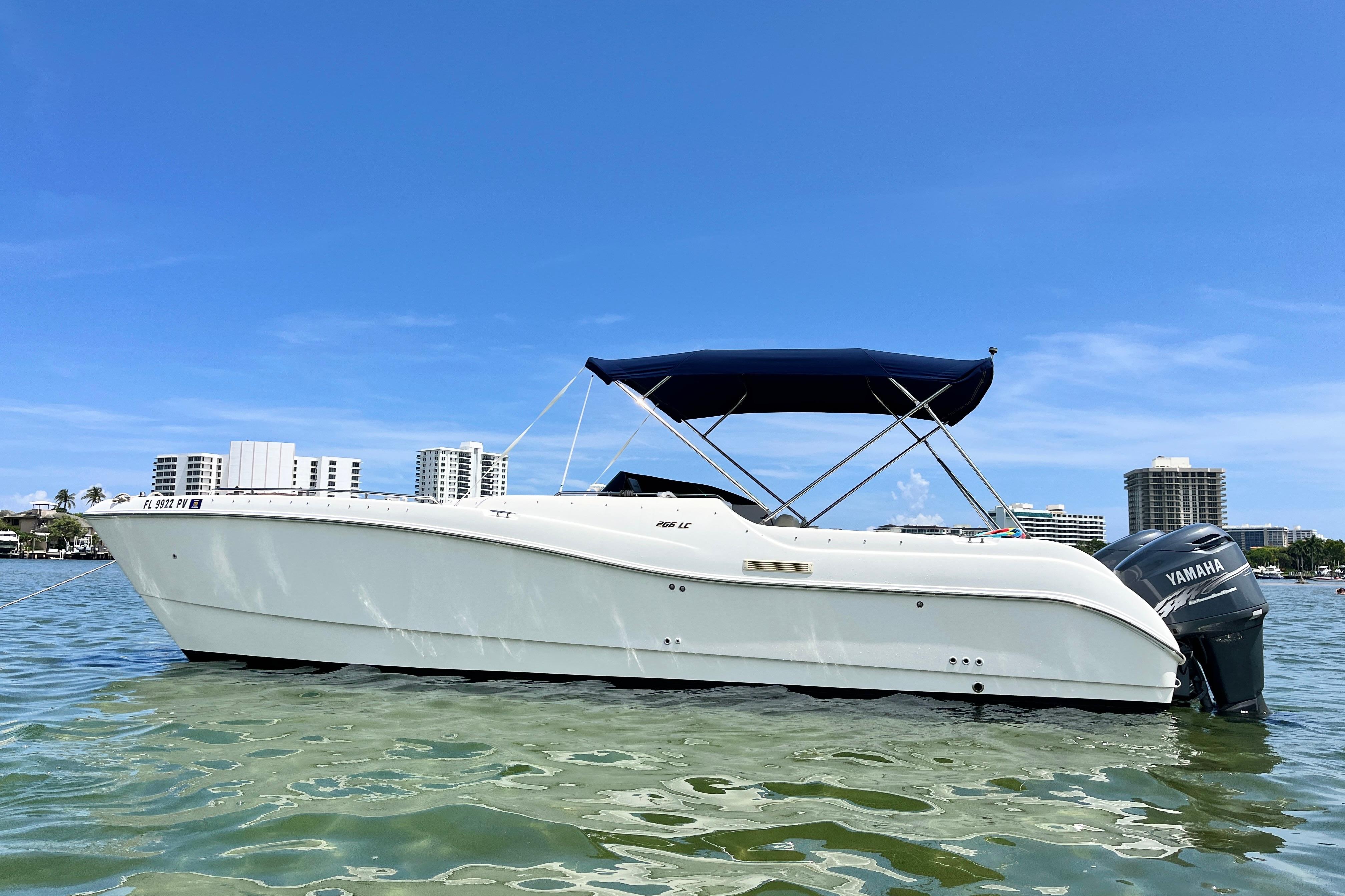 World Cat 266 Leisure Cat WorldCat 266 LC 2000 boat with Yamaha engine on calm water, cityscape background.