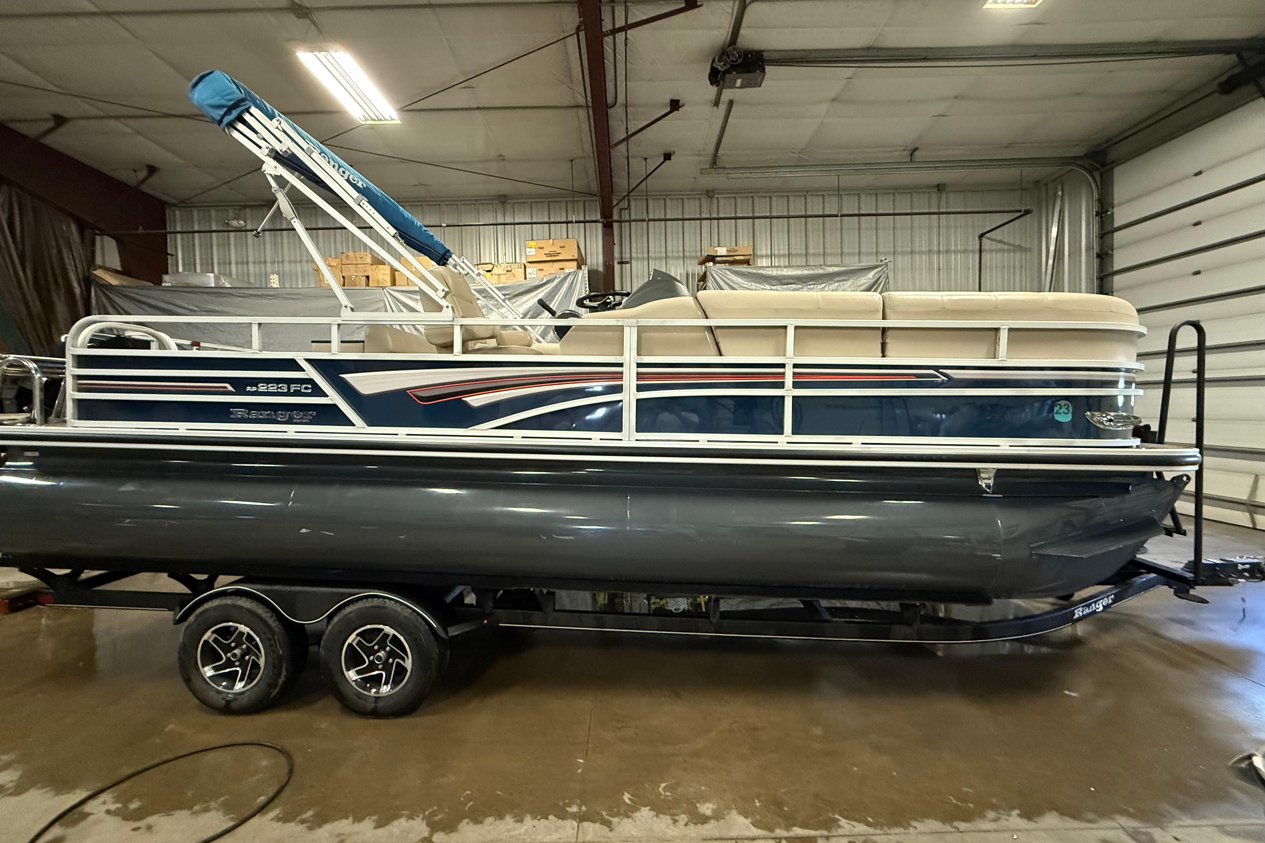 Ranger 223FC 2021 Ranger 223FC pontoon boat in a garage, featuring a blue and beige design.