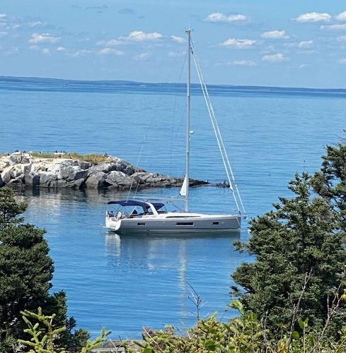 Beneteau 51.1 2019 Beneteau 51.1 sailboat anchored near rocky shoreline, surrounded by calm blue waters.