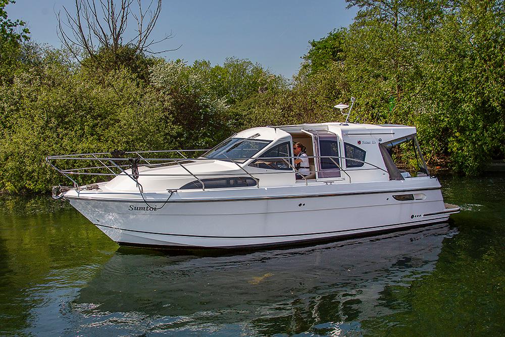 Haines 32 SEDAN 2023 Haines 32 SEDAN boat cruising on a serene river surrounded by lush greenery.