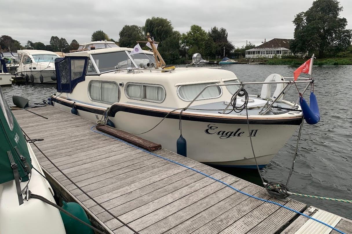 Freeman 26 1972 Freeman 26 boat "Eagle II" docked on a calm river with overcast skies.