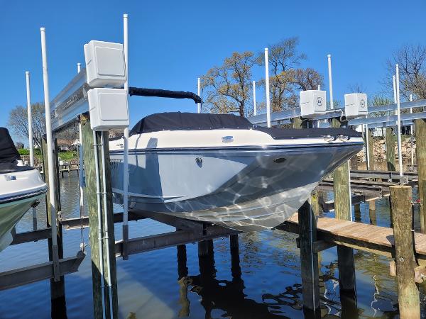 Bayliner D22 2025 Bayliner D22 boat on lift at dock, under clear blue sky.