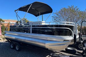 Sun Tracker Fishin' Barge 20 DLX 2026 Sun Tracker Fishin' Barge 20 DLX pontoon boat on trailer, under clear blue sky.
