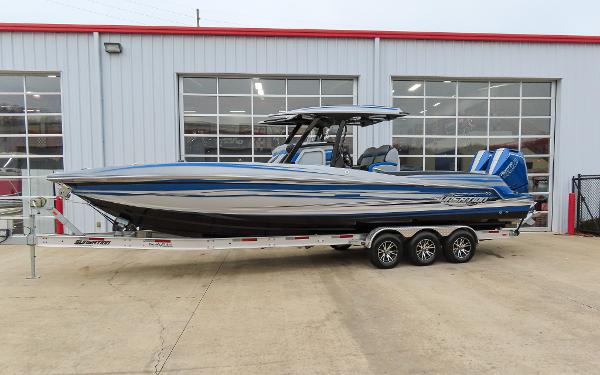 Sunsation 32CCX 2024 Sunsation 32CCX boat on trailer, parked outside a garage.