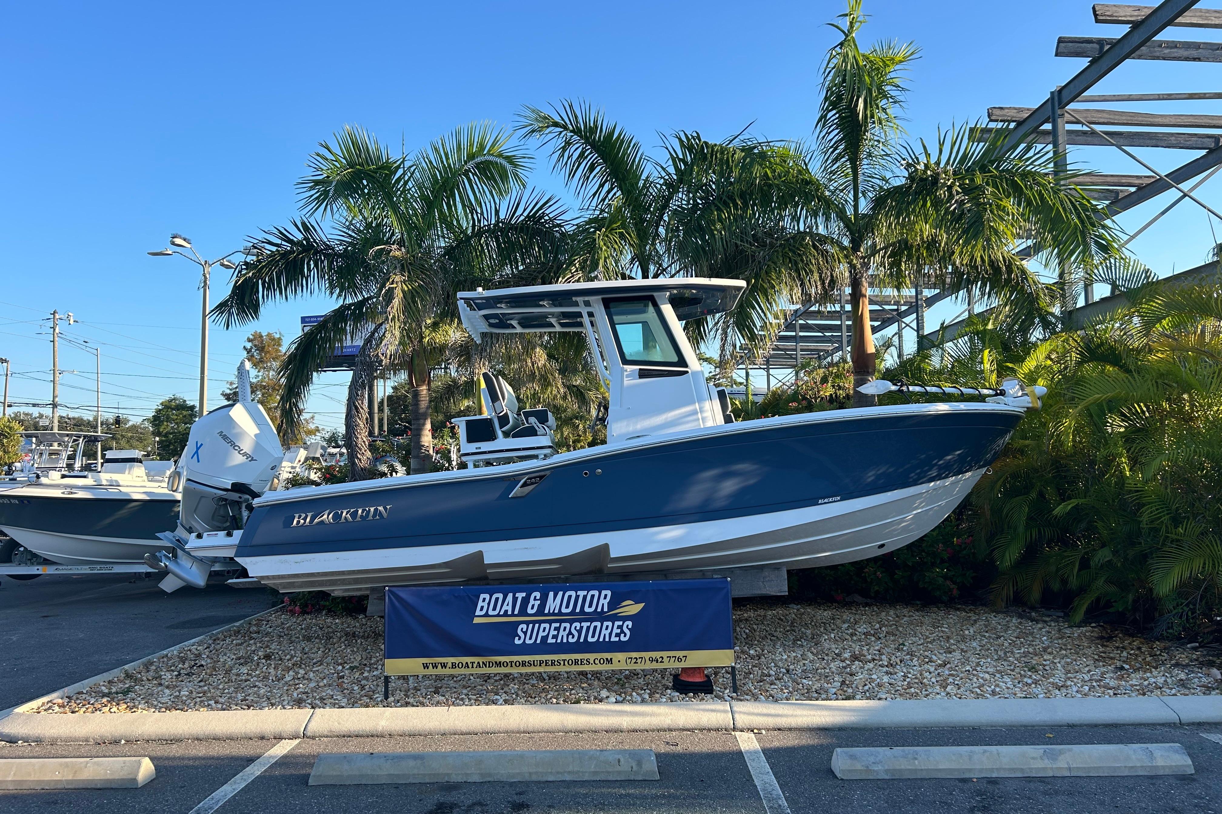 Blackfin 242 HB 2026 Blackfin 242 HB boat displayed at dealership, surrounded by palm trees.