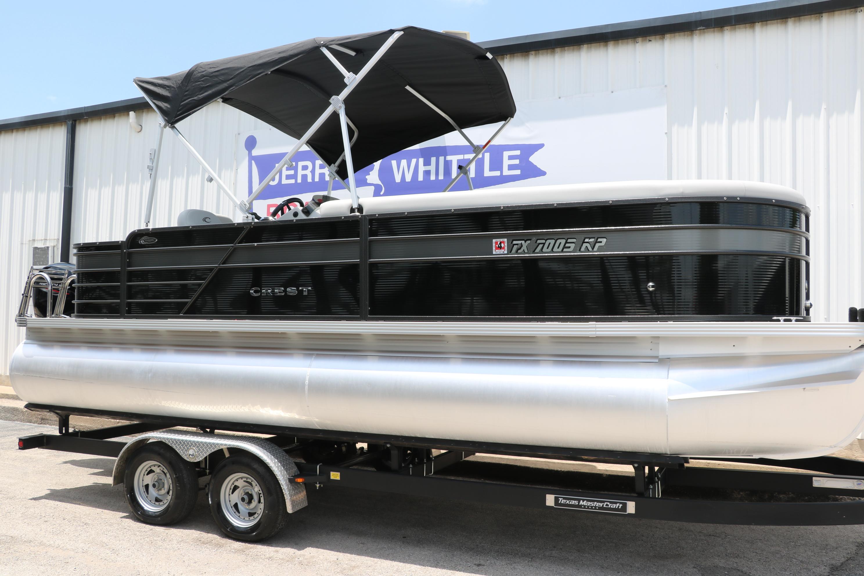 Crest Classic Fish 220 2022 Crest Classic Fish 220 pontoon boat on trailer, black canopy, parked outdoors.
