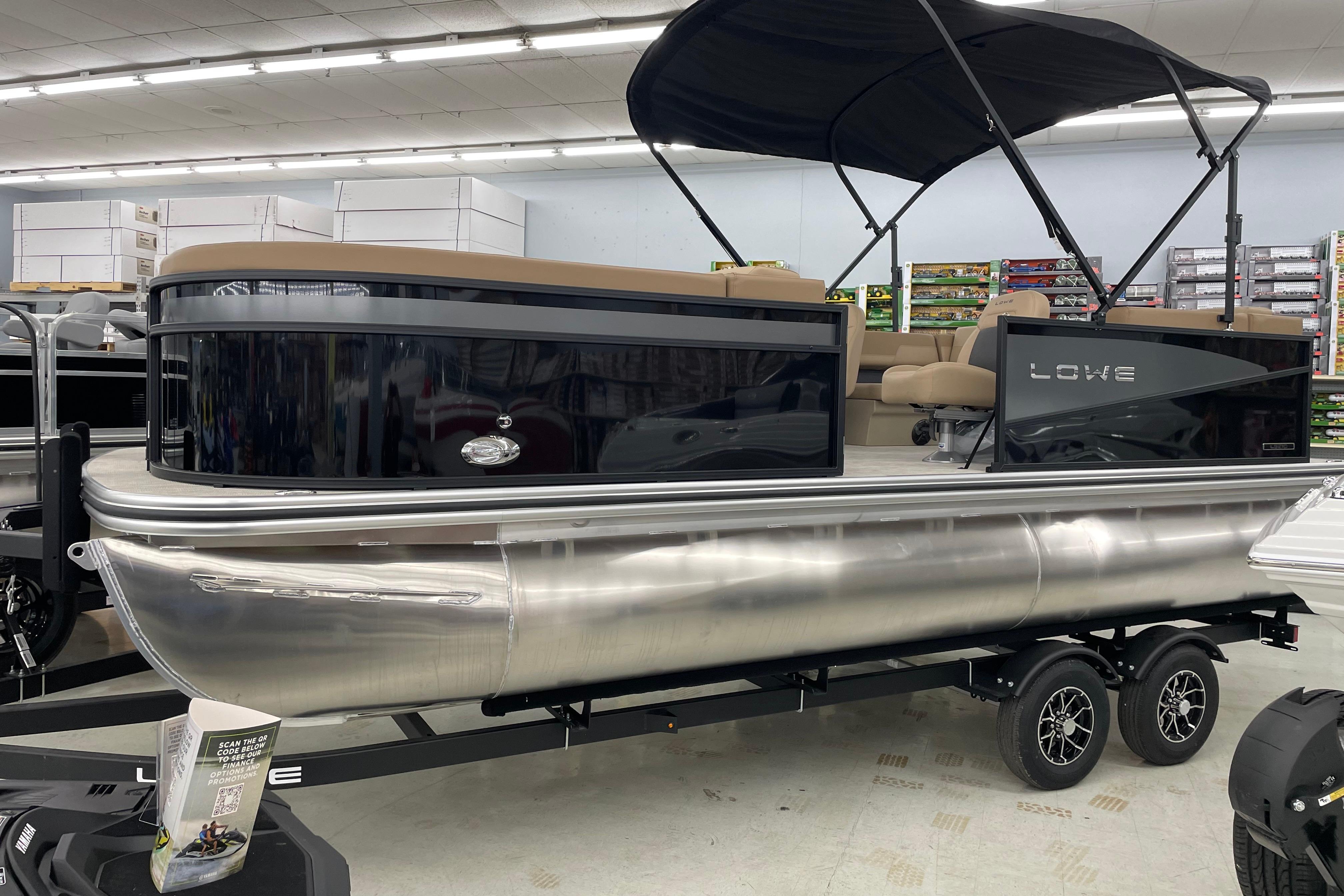 Lowe LS210W 2026 Lowe LS210W pontoon boat with canopy displayed indoors on a trailer.