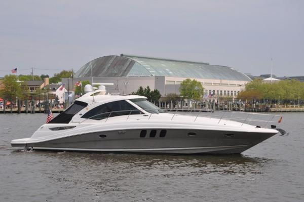 Sea Ray 48 Sundancer 2006 Sea Ray 48 Sundancer yacht cruising on a calm river near a modern building.
