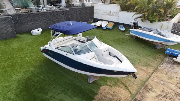 Cobalt R3 2020 Cobalt R3 boat with blue canopy on grass, surrounded by other boats and equipment.