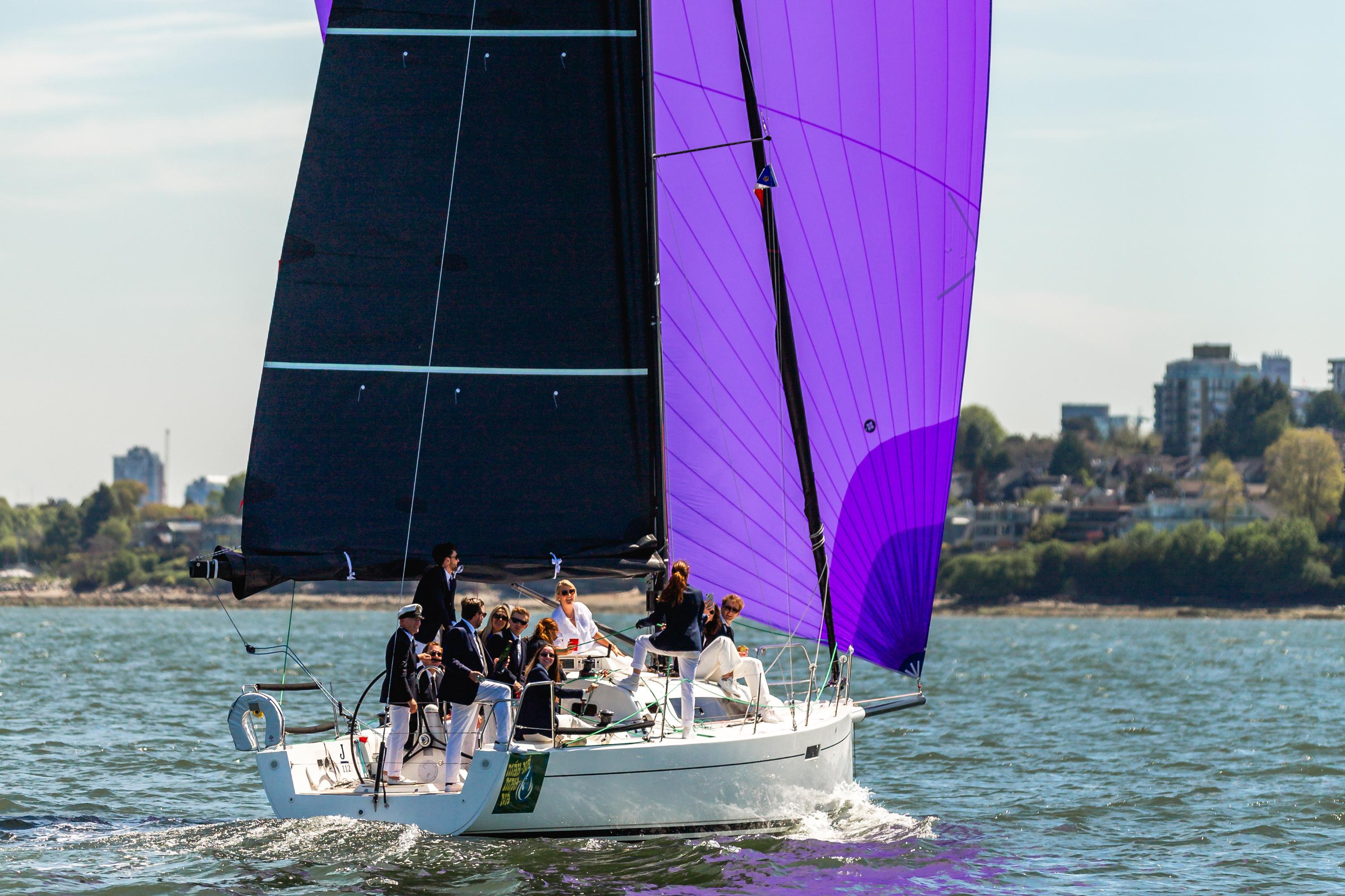 J Boats J/112E Sailing on a 2020 J Boats J/112E with vibrant purple spinnaker, near coastal cityscape.