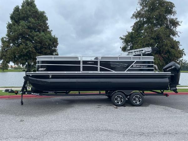 Ranger Reata 223C 2024 Ranger Reata 223C pontoon boat on trailer by a lake.