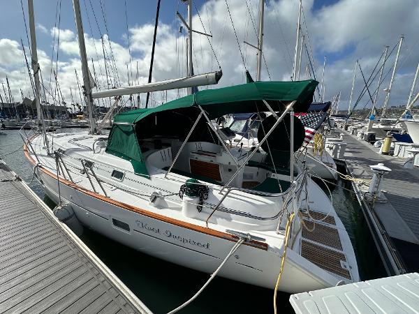 Beneteau 411 2002 Beneteau 411 sailboat docked at marina, featuring green canopy and sleek design.