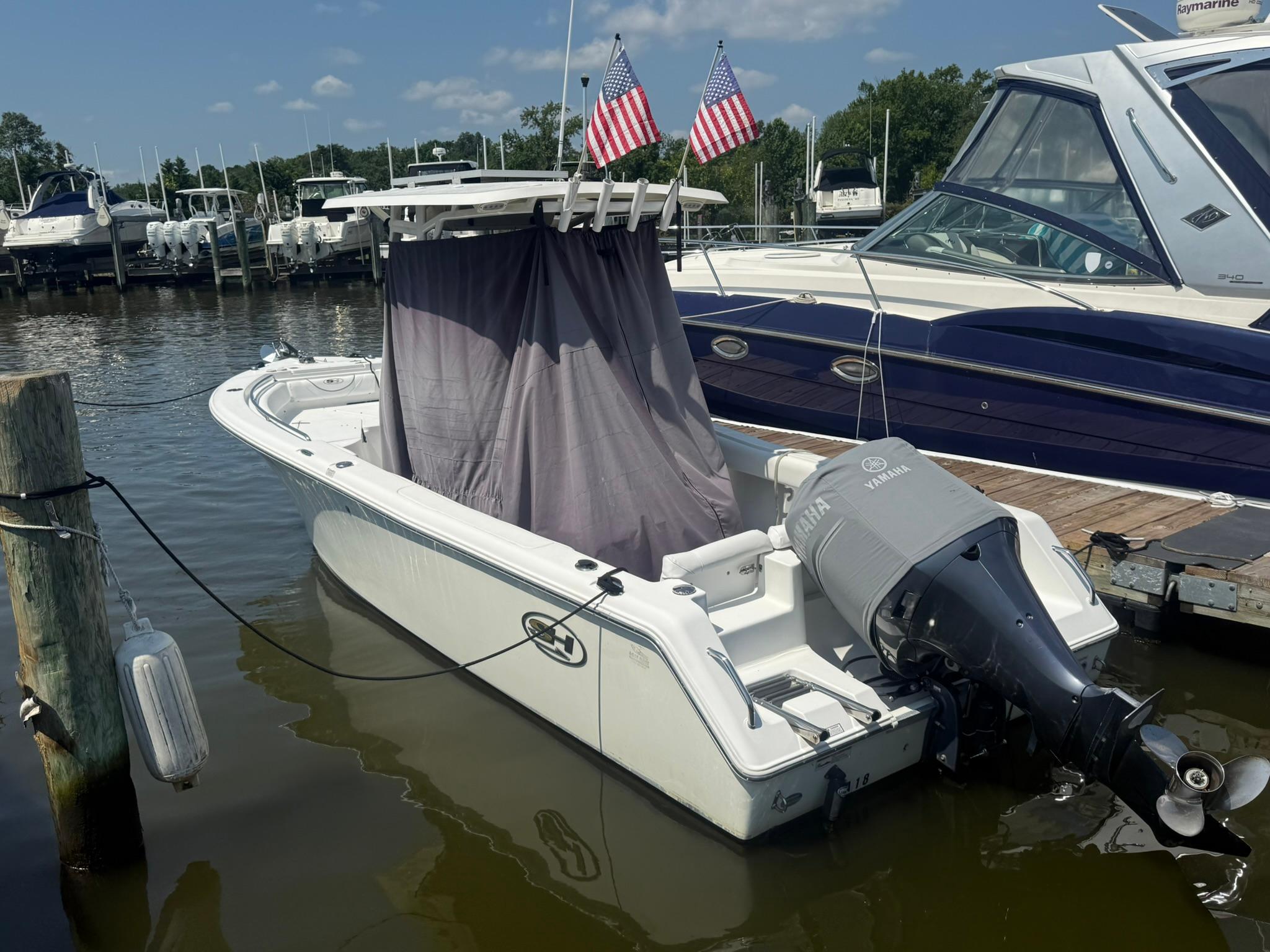 Sea Hunt Ultra 234 2017 Sea Hunt Ultra 234 boat docked with Yamaha outboard motor and American flags.