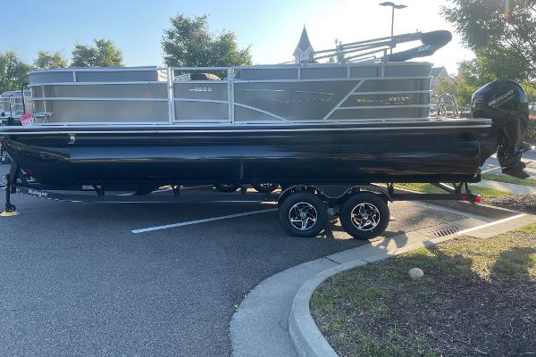 Ranger Reata 223C 2024 Ranger Reata 223C pontoon boat on trailer in parking lot.