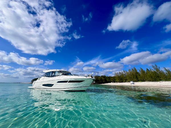 Regal 38 XO 2022 Regal 38 XO yacht on clear turquoise water near a sandy beach under a blue sky.