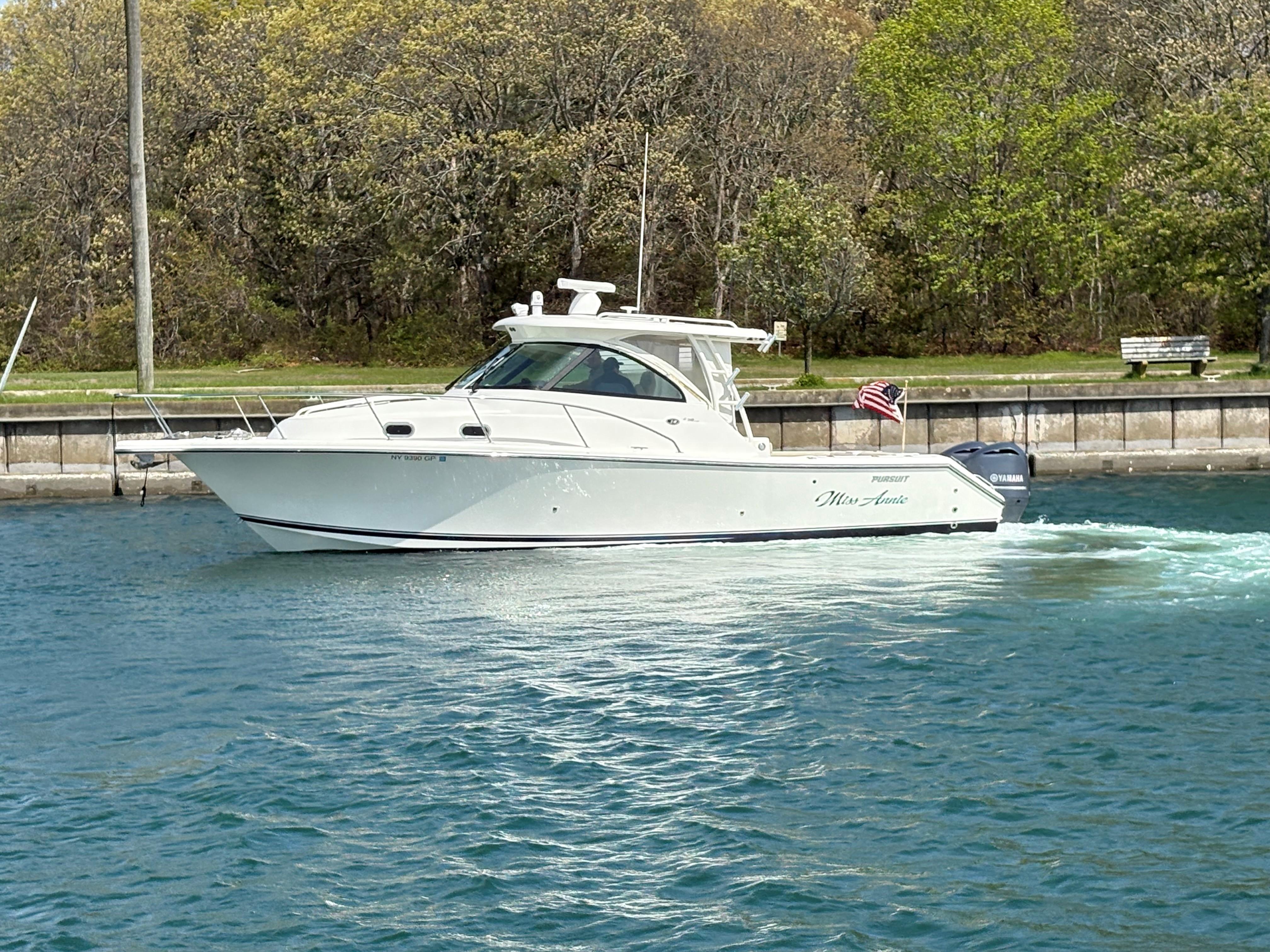 Pursuit OS 345 Offshore 2015 Pursuit OS 345 Offshore boat cruising on a calm waterway, surrounded by lush greenery.
