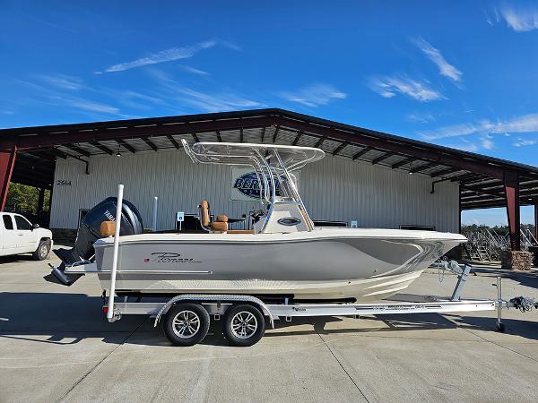 Pioneer 222 Sportfish 2025 Pioneer 222 Sportfish boat on trailer, parked outside a warehouse under clear blue sky.