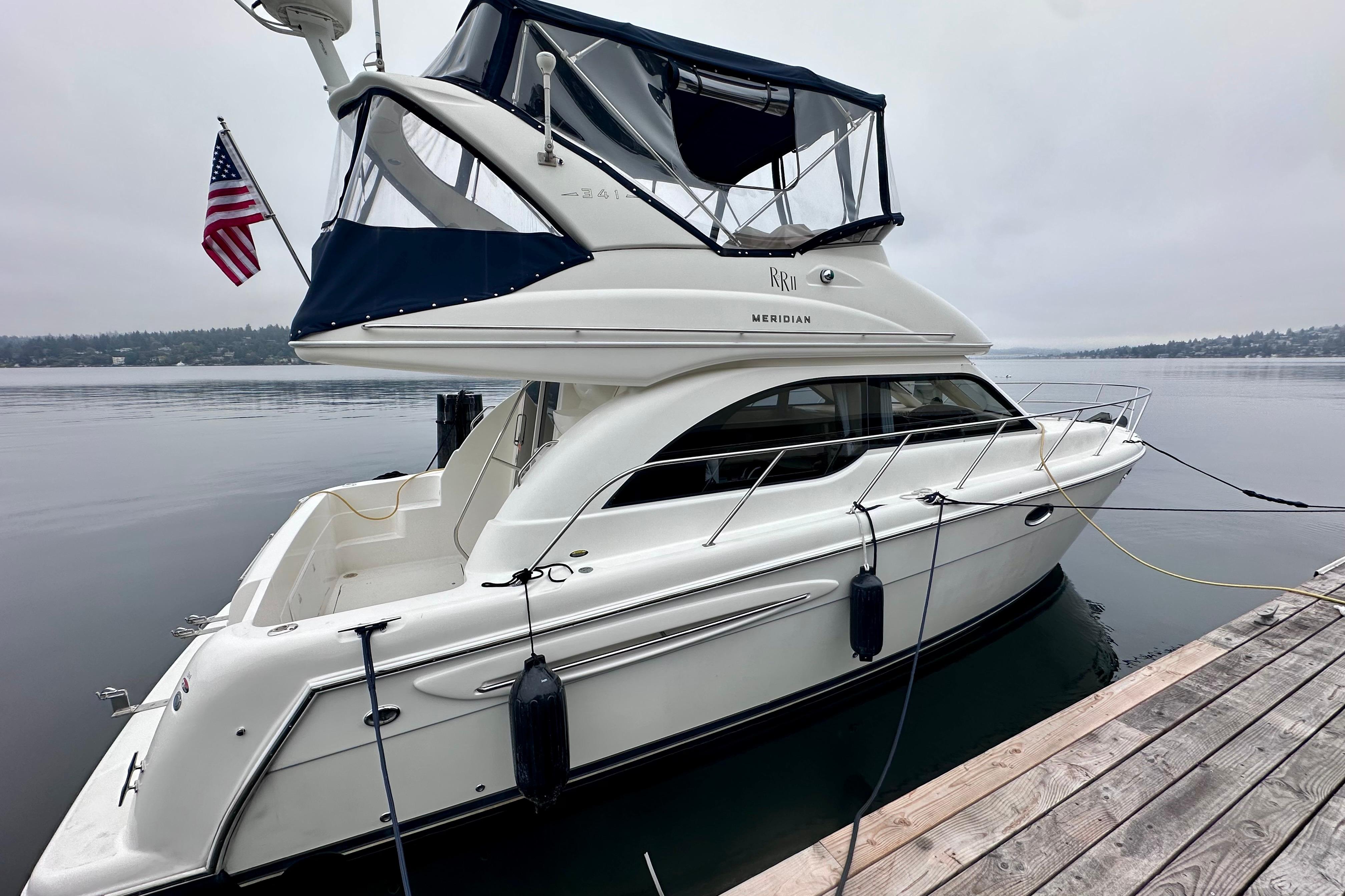 Meridian 341 Sedan 2003 Meridian 341 Sedan yacht docked on a calm lake with an American flag.
