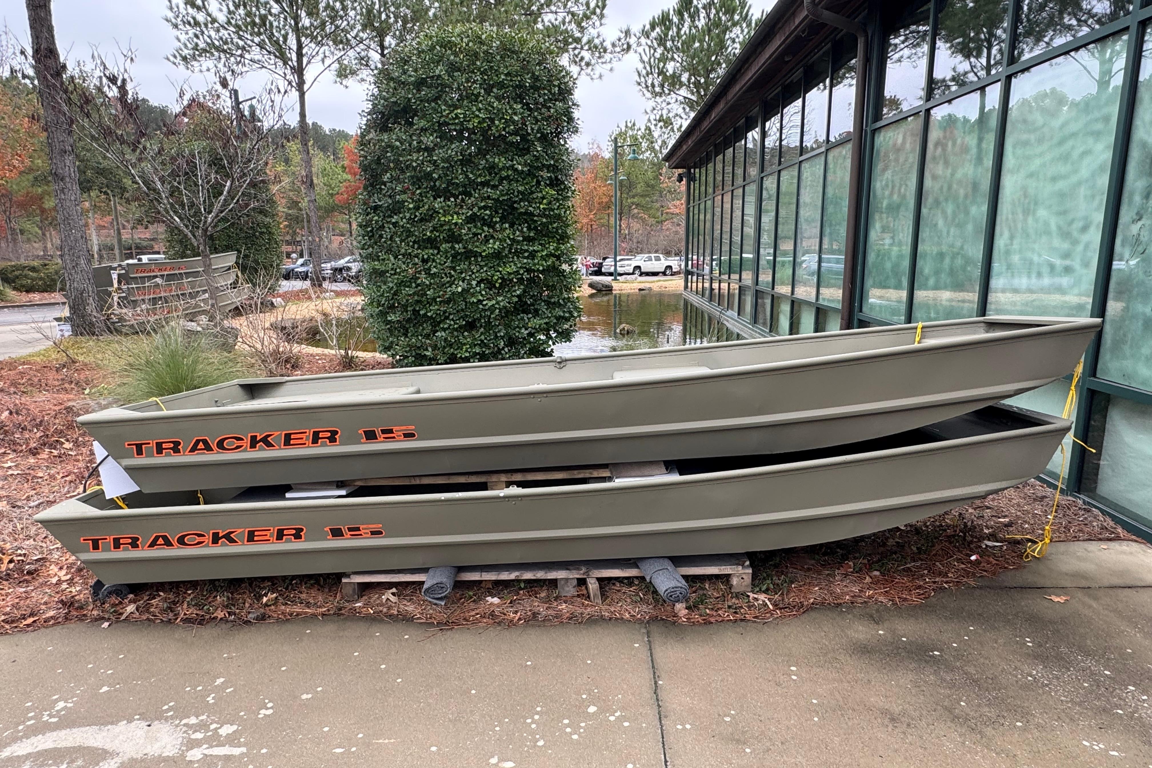 Tracker Grizzly 15 Jon 2026 Tracker Grizzly 15 Jon boats stacked outdoors near a glass building.