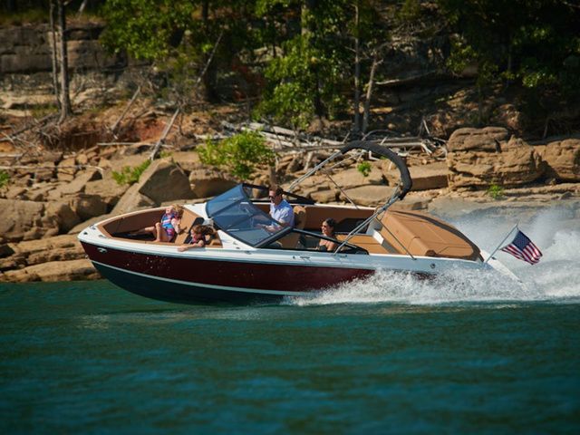 Cobalt CS22 2025 Cobalt CS22 boat cruising on a lake with passengers, near rocky shoreline.