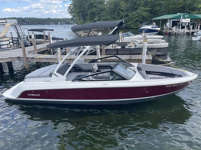 Cobalt CS22 2025 Cobalt CS22 boat docked on a lake, featuring a sleek design and maroon exterior.