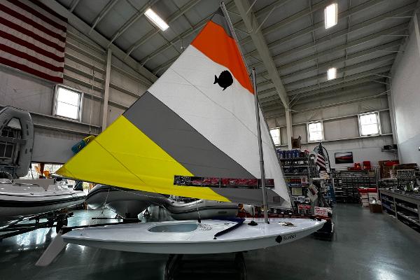Sunfish / Laser Sailboat 2024 Sunfish Laser sailboat with colorful sail displayed indoors.