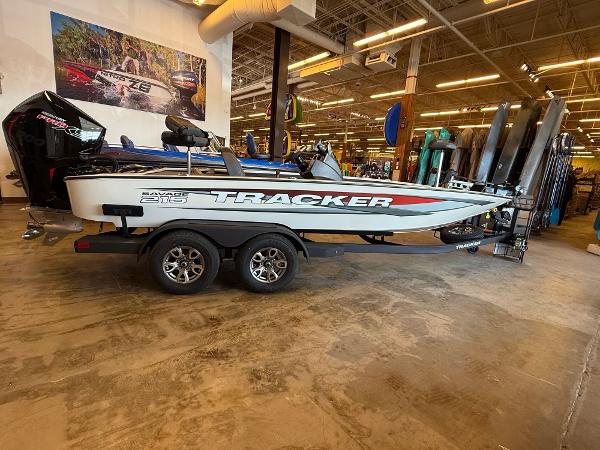 Tracker Savage 215 2025 Tracker Savage 215 boat on trailer in showroom, featuring sleek design and modern features.