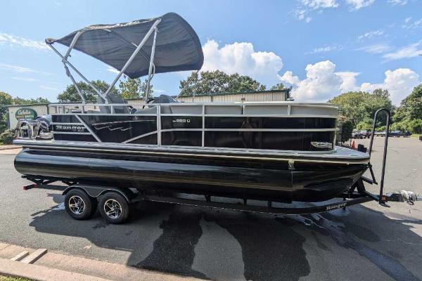 Ranger Reata 223C 2024 Ranger Reata 223C pontoon boat with canopy on trailer, parked outdoors.
