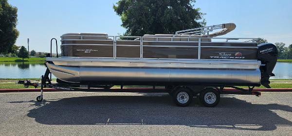 Sun Tracker SportFish 22 DLX 2024 Sun Tracker SportFish 22 DLX pontoon boat on trailer by a lake.