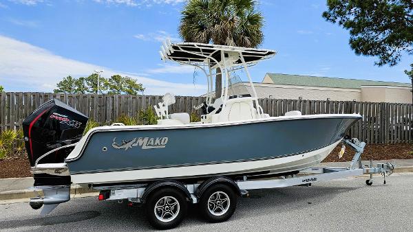 Mako 214 CC 2024 Mako 214 CC boat on trailer, parked outdoors, with palm trees in the background.