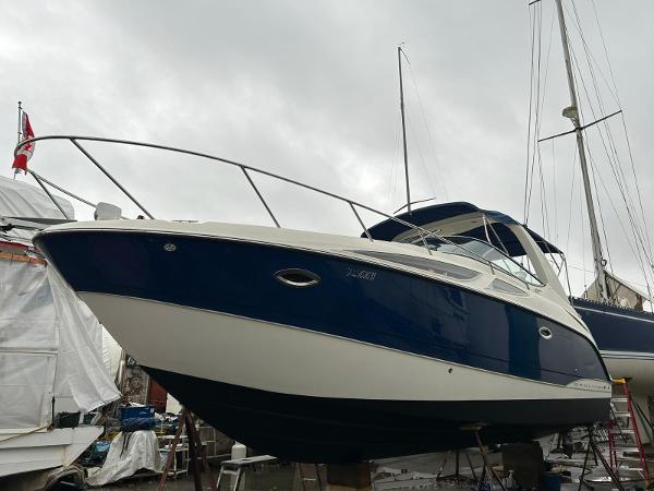 Bayliner 300 2008 Bayliner 300 boat on dry dock, blue and white hull, overcast sky.