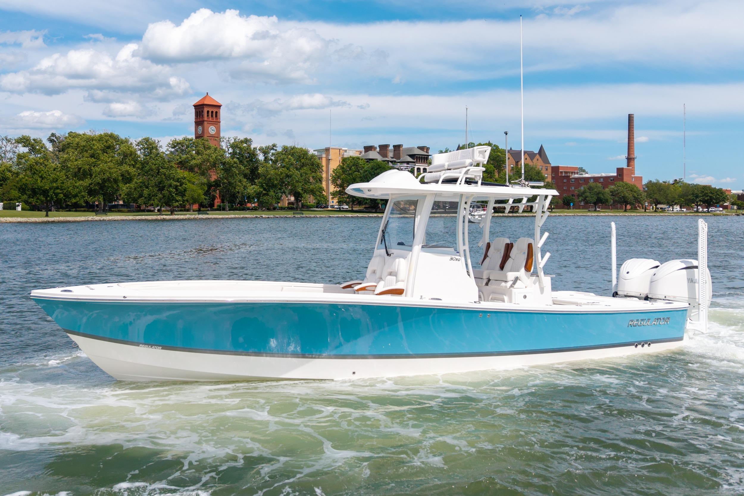 Regulator 30XO 2023 Regulator 30XO boat cruising on a scenic river with cityscape background.