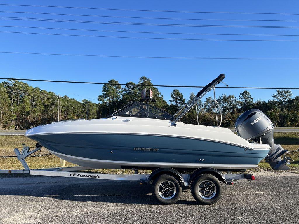 Stingray 201DC 2025 Stingray 201DC boat on trailer, blue and white design, parked outdoors.