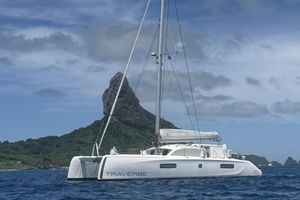 Outremer 51 2021 Outremer 51 catamaran sailing near a rocky island under a cloudy sky.